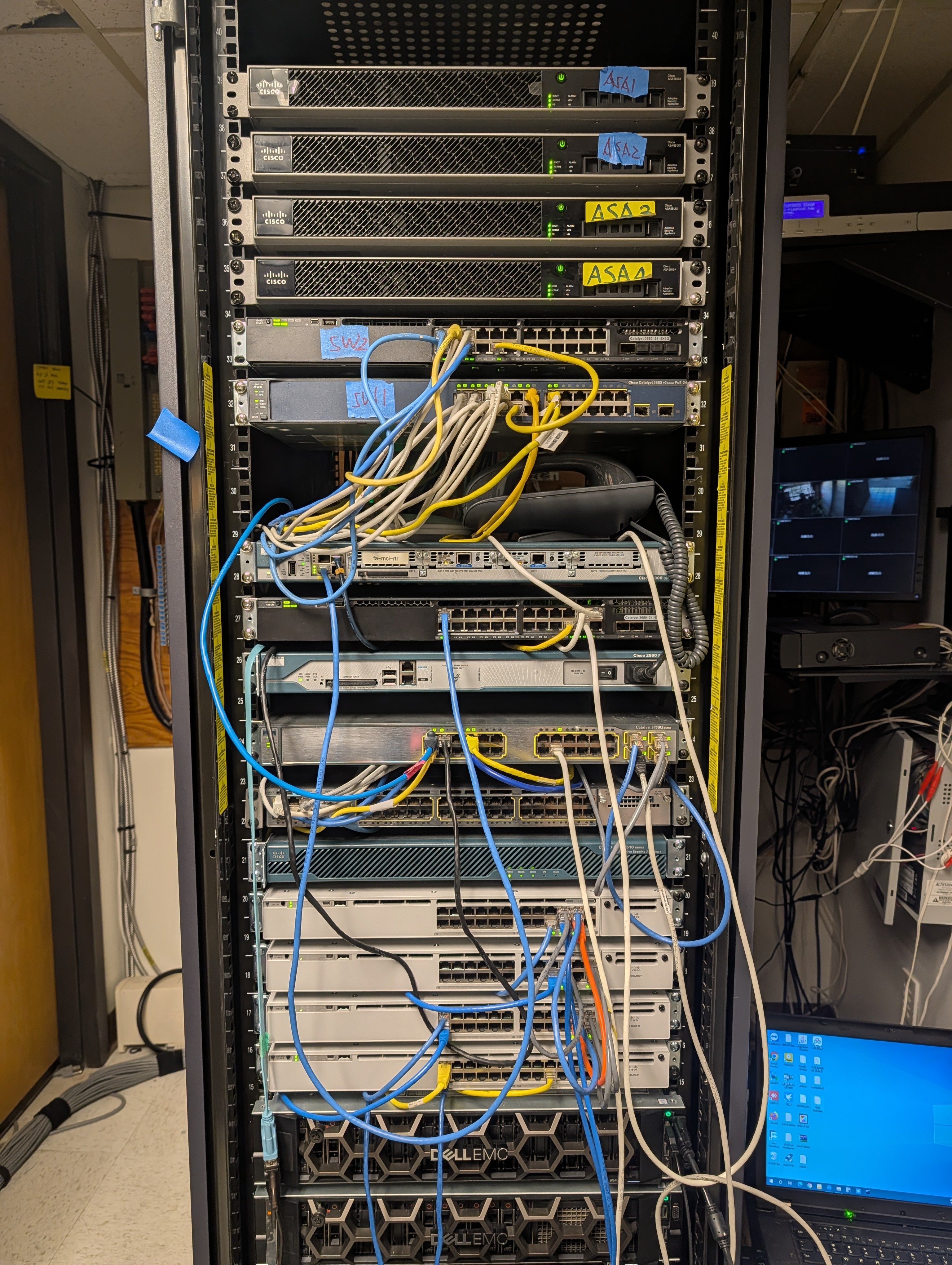 LaneCert lab rack with Cisco networking equipment, firewalls, switches, and patch cabling used for hands-on practice.